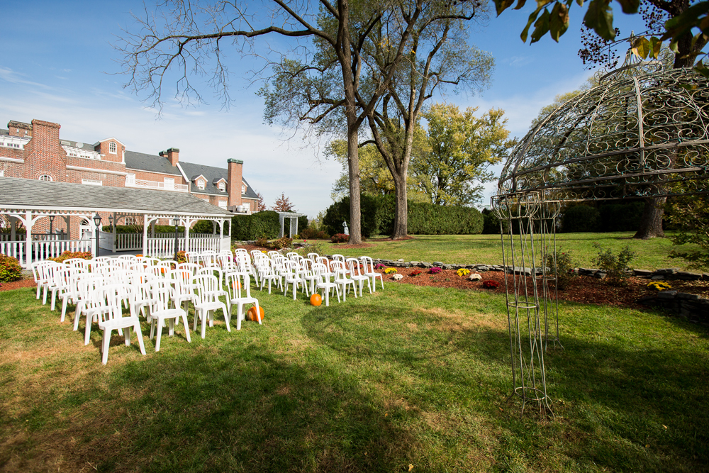 wedding ceremony set up with white chairs and pumpkins