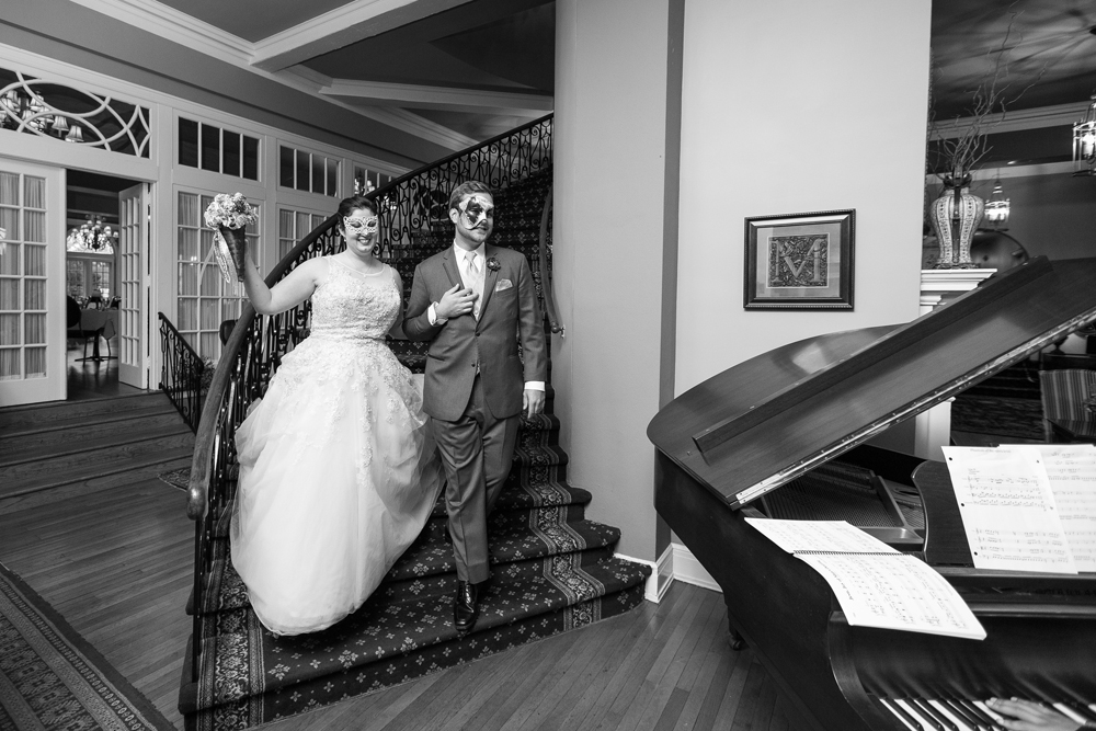 bride and groom walking down mimslyn inn staircase in masquerade masks
